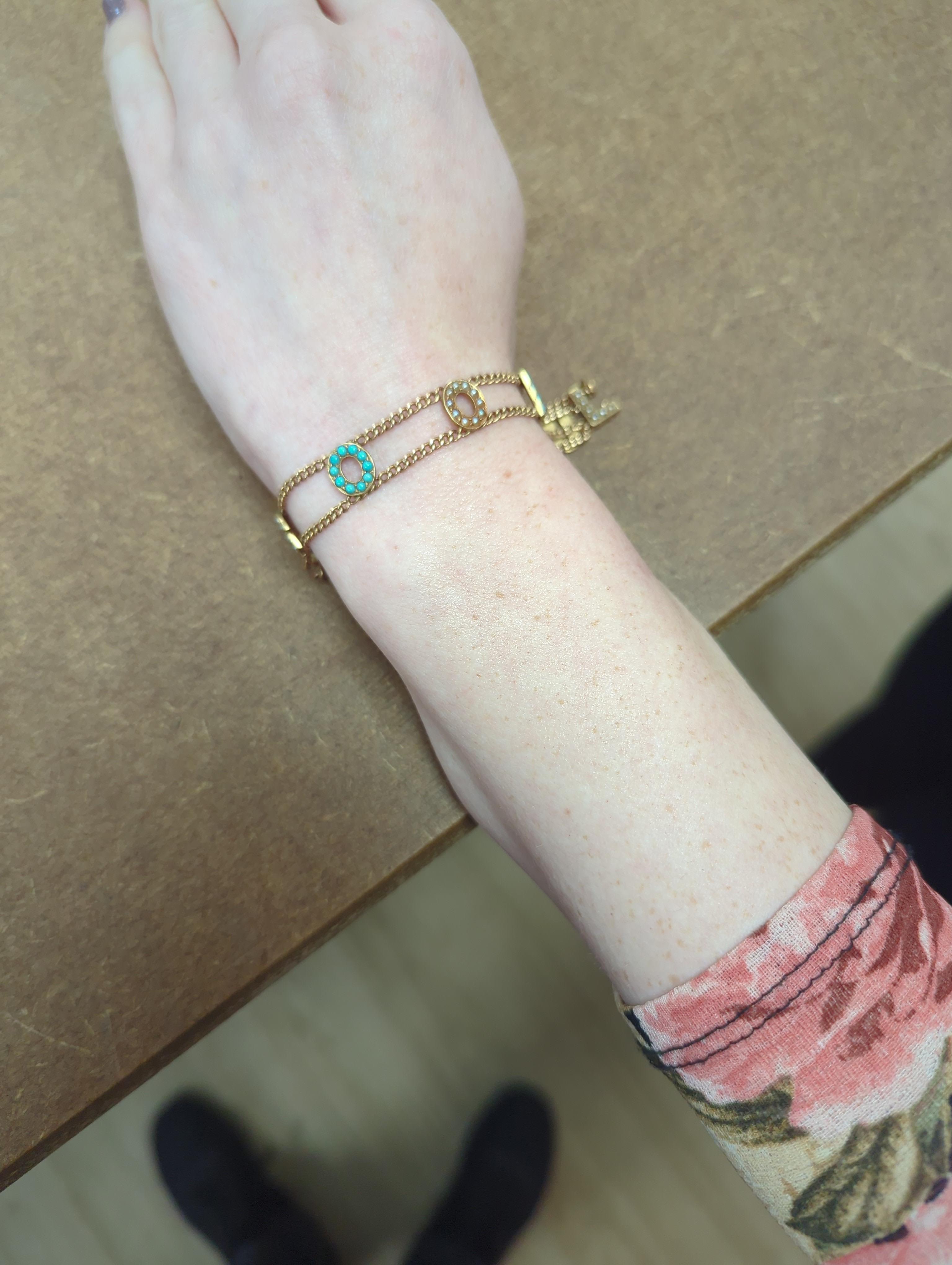 An Edwardian 15ct?, turquoise and seed pearl set 'Good Luck' chain bracelet, 17cm and a yellow metal and seed pearl set 'Baby' bar brooch.